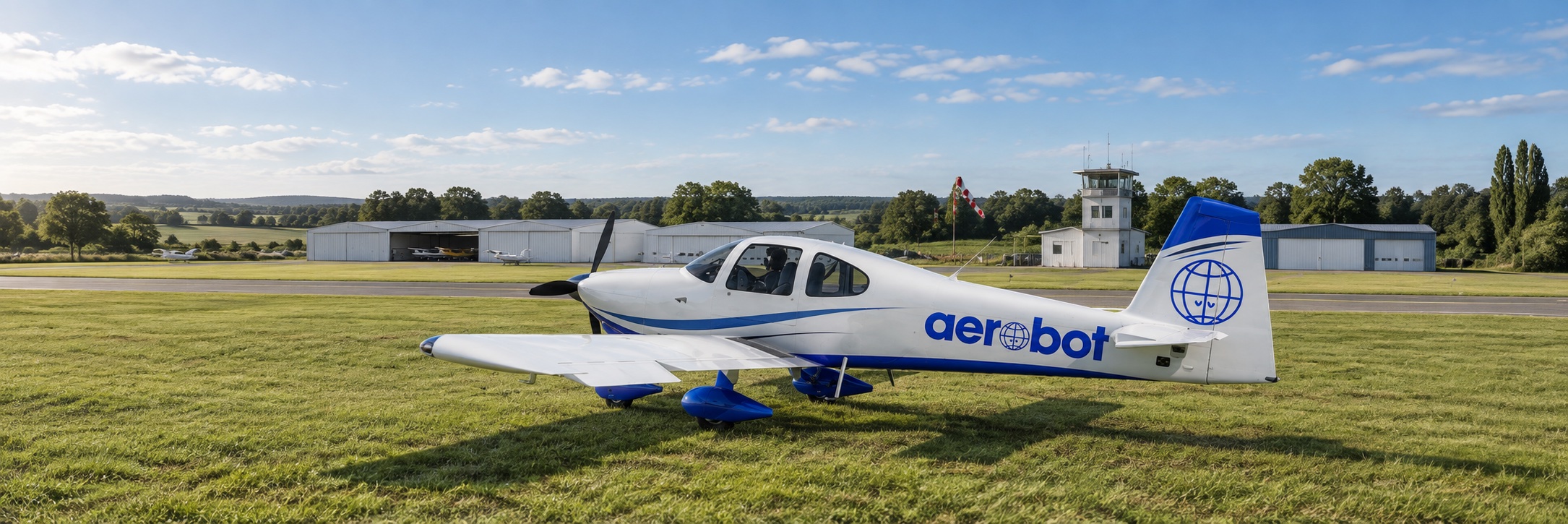 Illustration Aerobot : un avion léger blanc et bleu sur l’herbe d’un aérodrome, sous un ciel lumineux.
